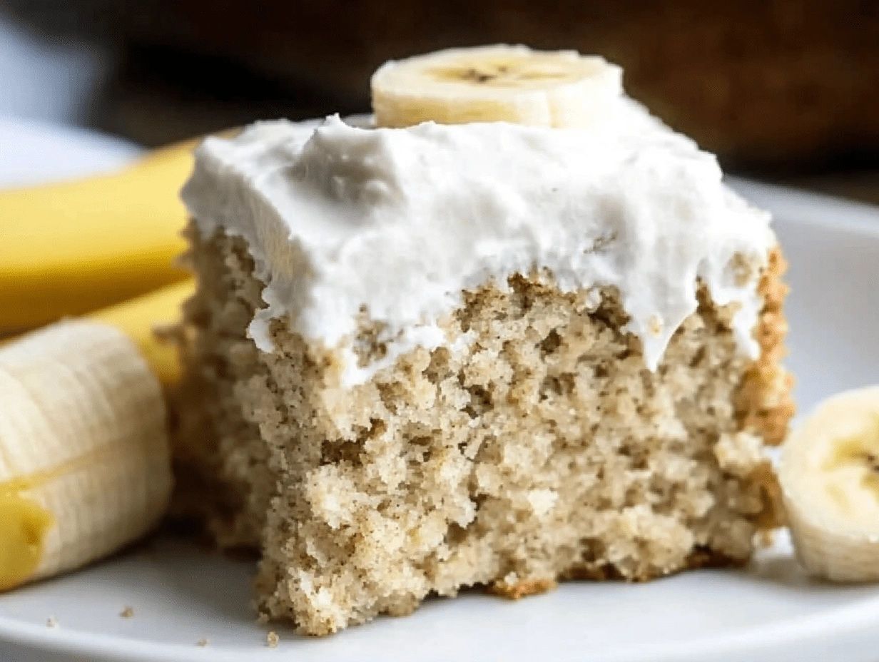 Close-up slice of moist healthy banana cake with creamy frosting and banana topping